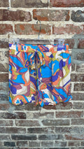 multicolored abstract-print shorts with a tie waist hanging against a brick wall