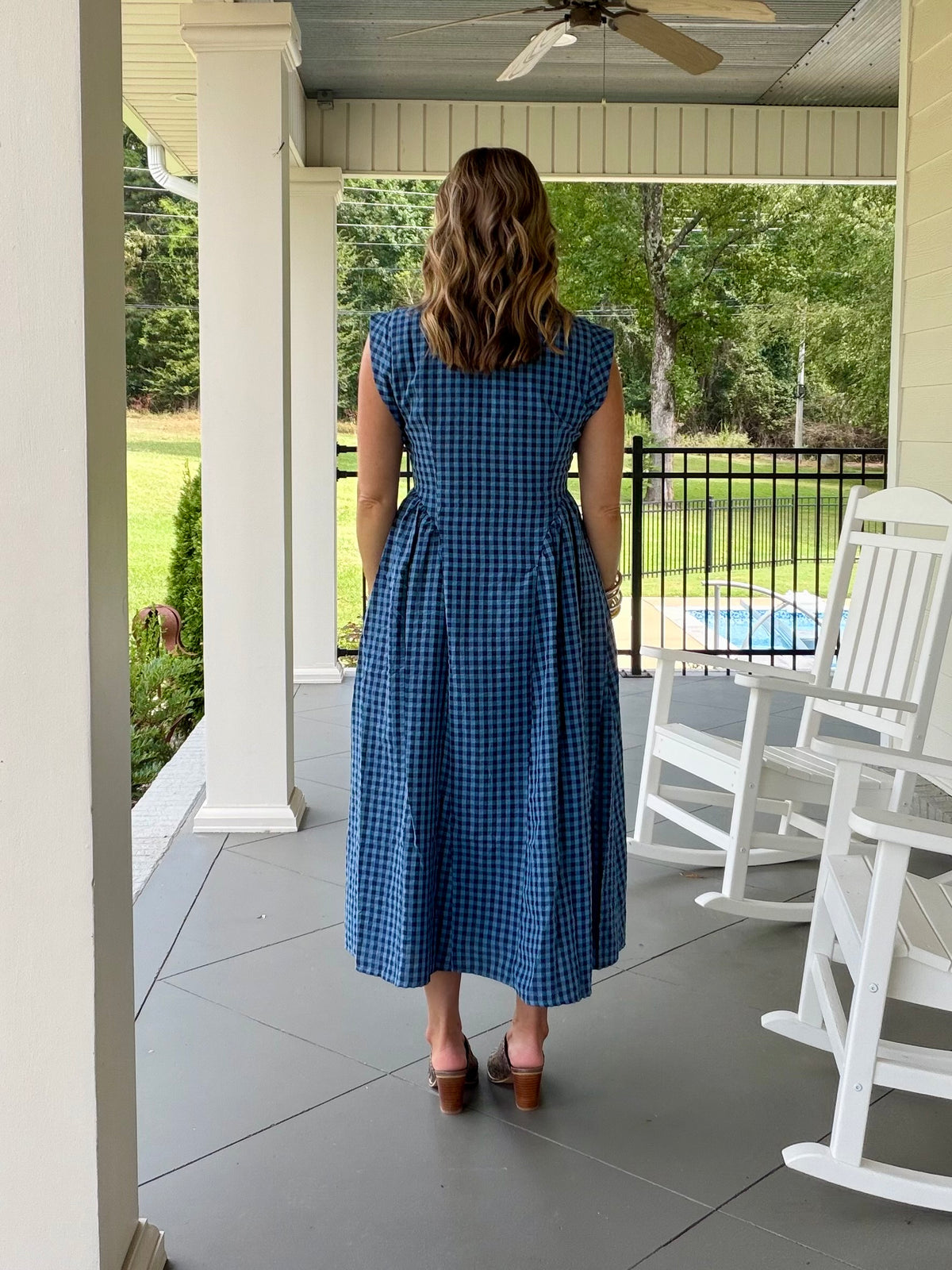 A beautiful sleeveless blue and white gingham midi dress with a button-front bodice, gathered waist, and skirt pockets.