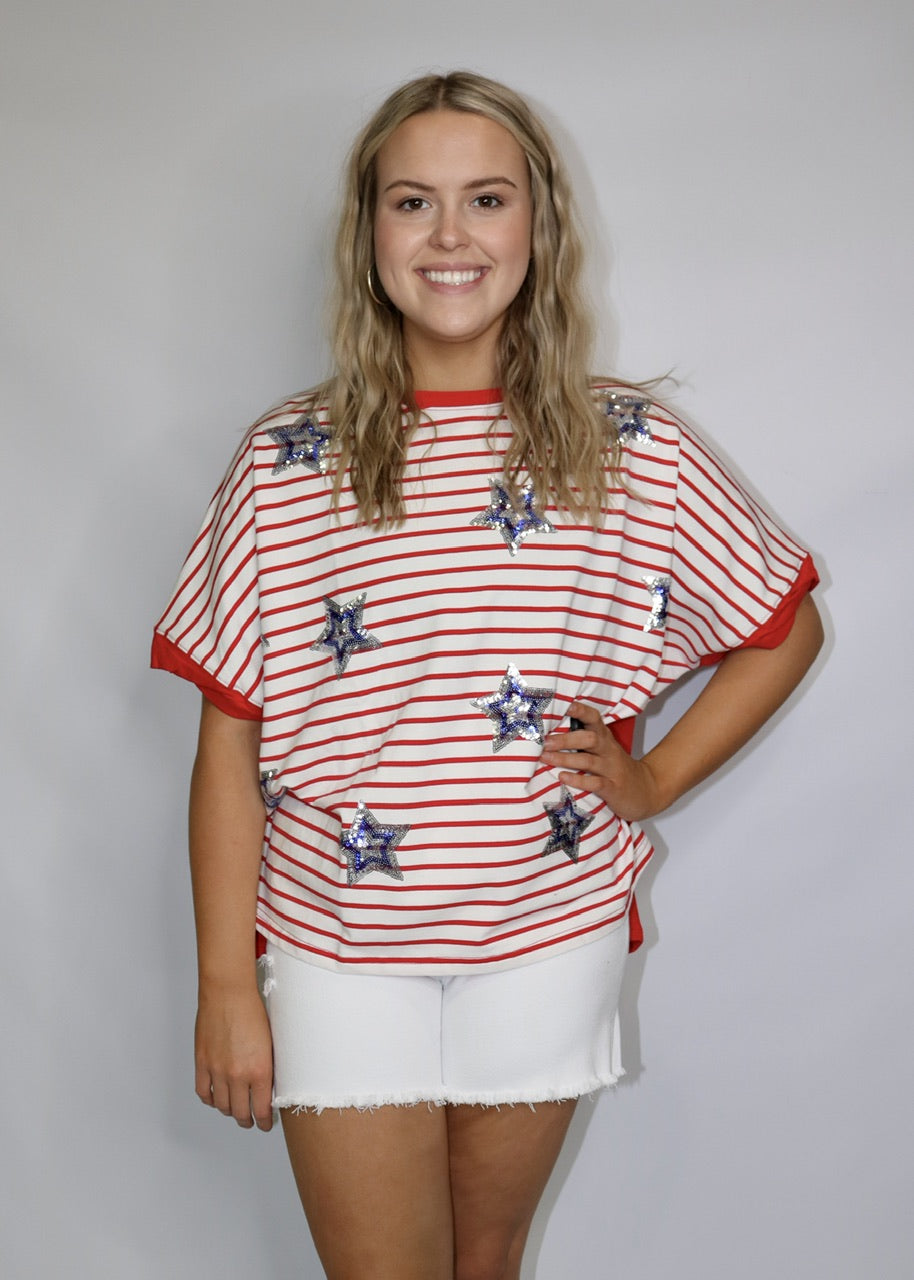 model wearing white frayed-hem denim shorts with a red striped star-print tee