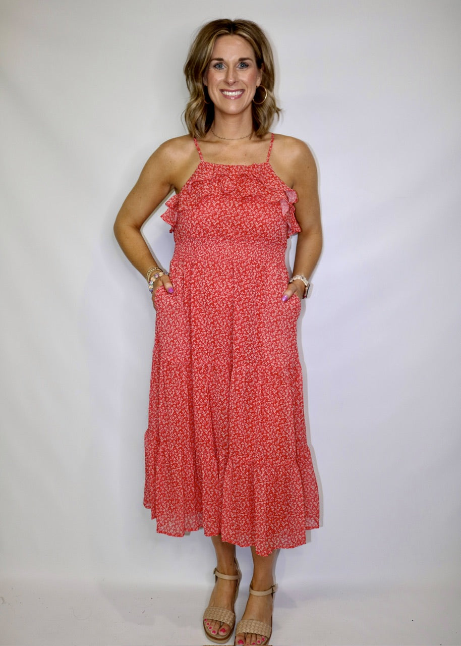 model wearing a red small-print midi dress with thin straps, neckline ruffles and side pockets