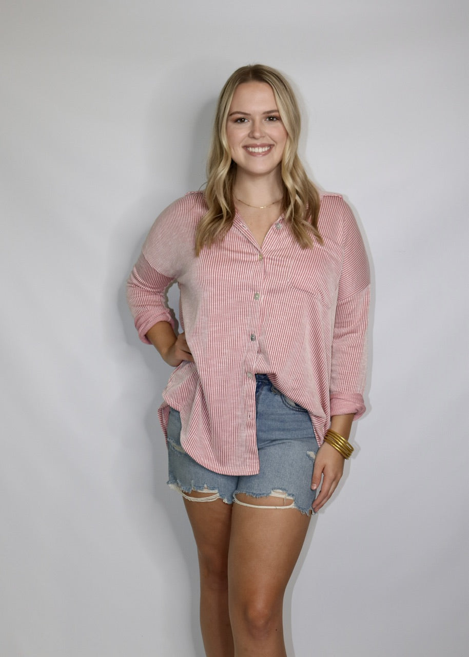 model wearing distressed denim cutoff shorts with a pink striped button-down shirt