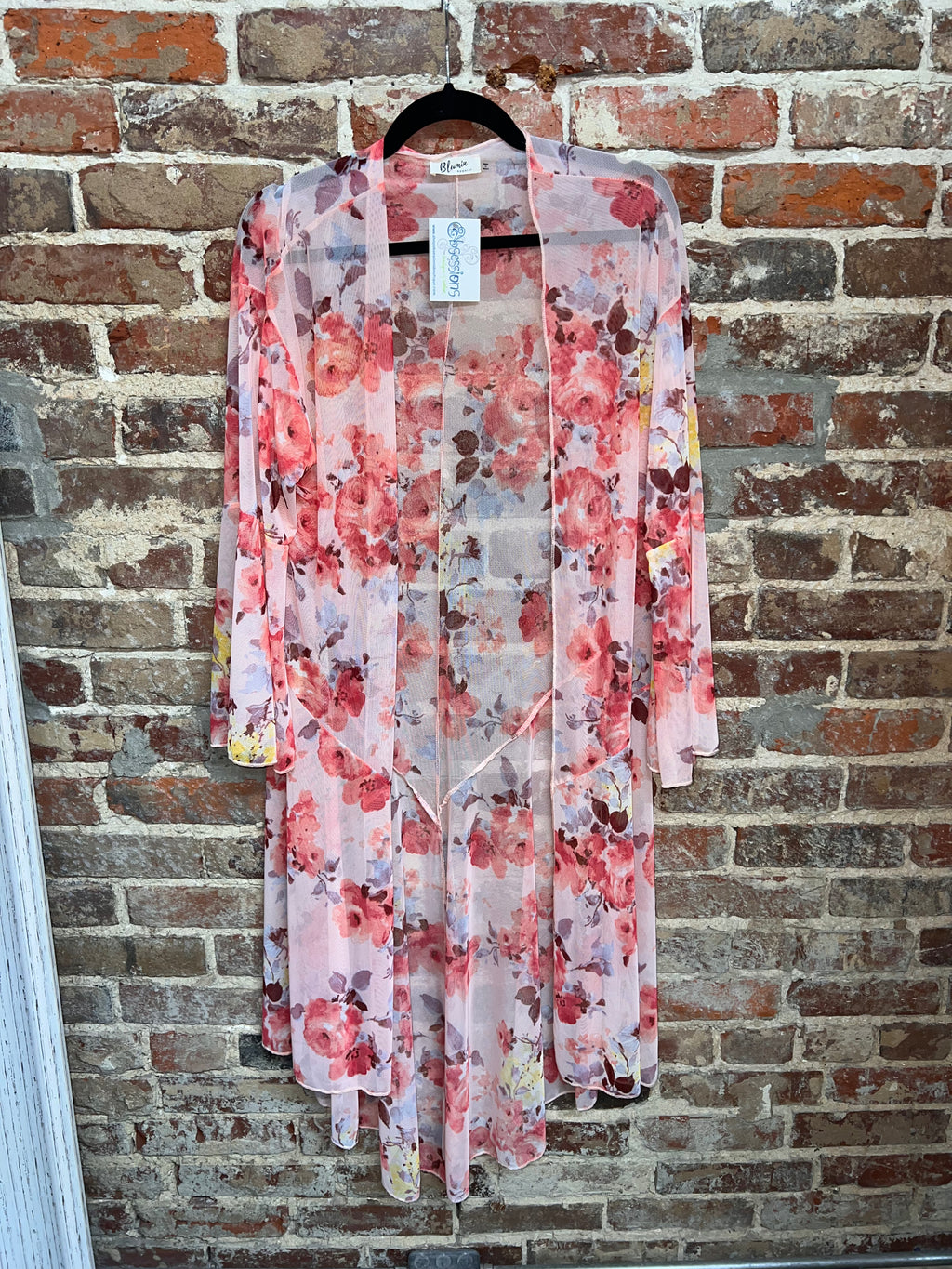 long sheer pink floral open-front kimono with flowing sleeves on a hanger