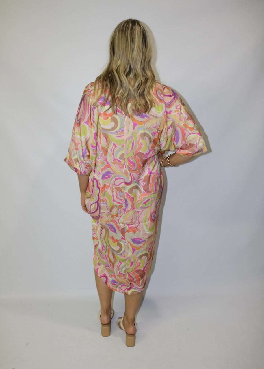 back view of a pink abstract-print midi dress with relaxed sleeves and a rounded hem