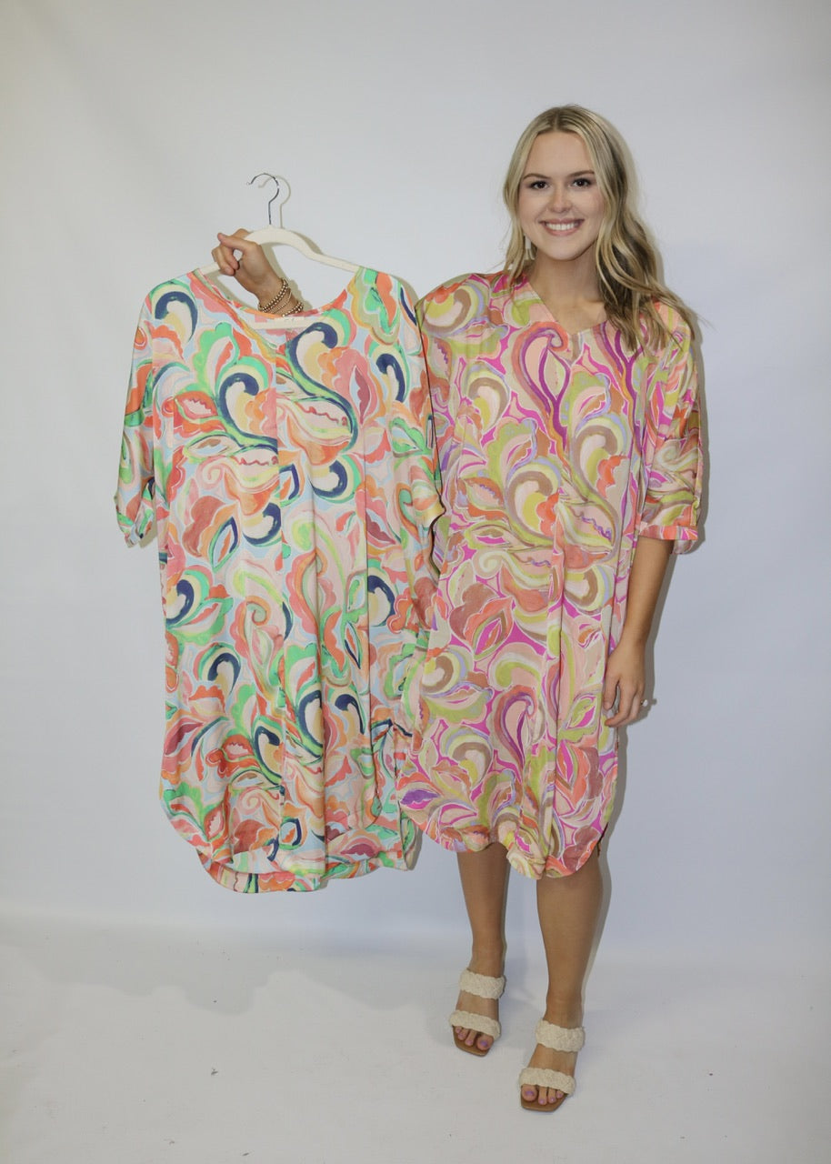 model wearing a pink abstract-print midi dress and holding a mint and coral color option